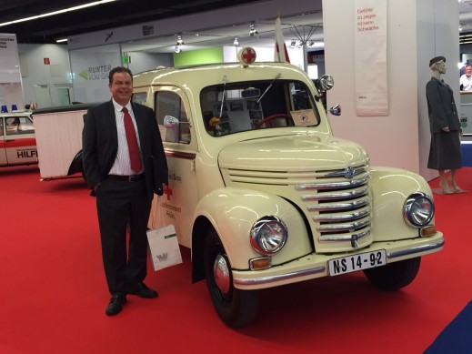LIASE Group President and Managing Director Europe Wolfgang Doell stands next to an antique ambulance at the 2015 IAA. 