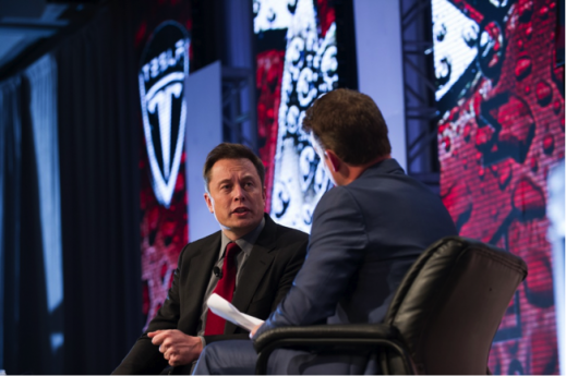 Elon Musk speaking at the Automotive News World Congress. Musk urged industry leaders to do more to advance the development of the electric car. 